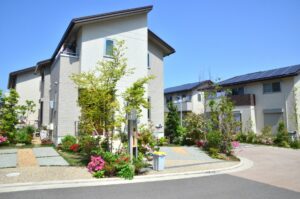 青空の下、庭木や花が彩る住宅街の一角